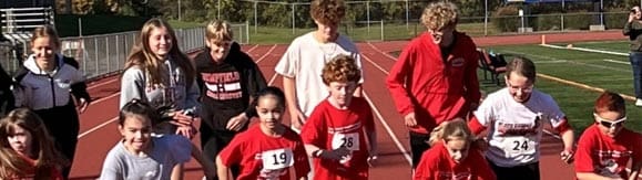 senior hempfield students training on the track with younger students